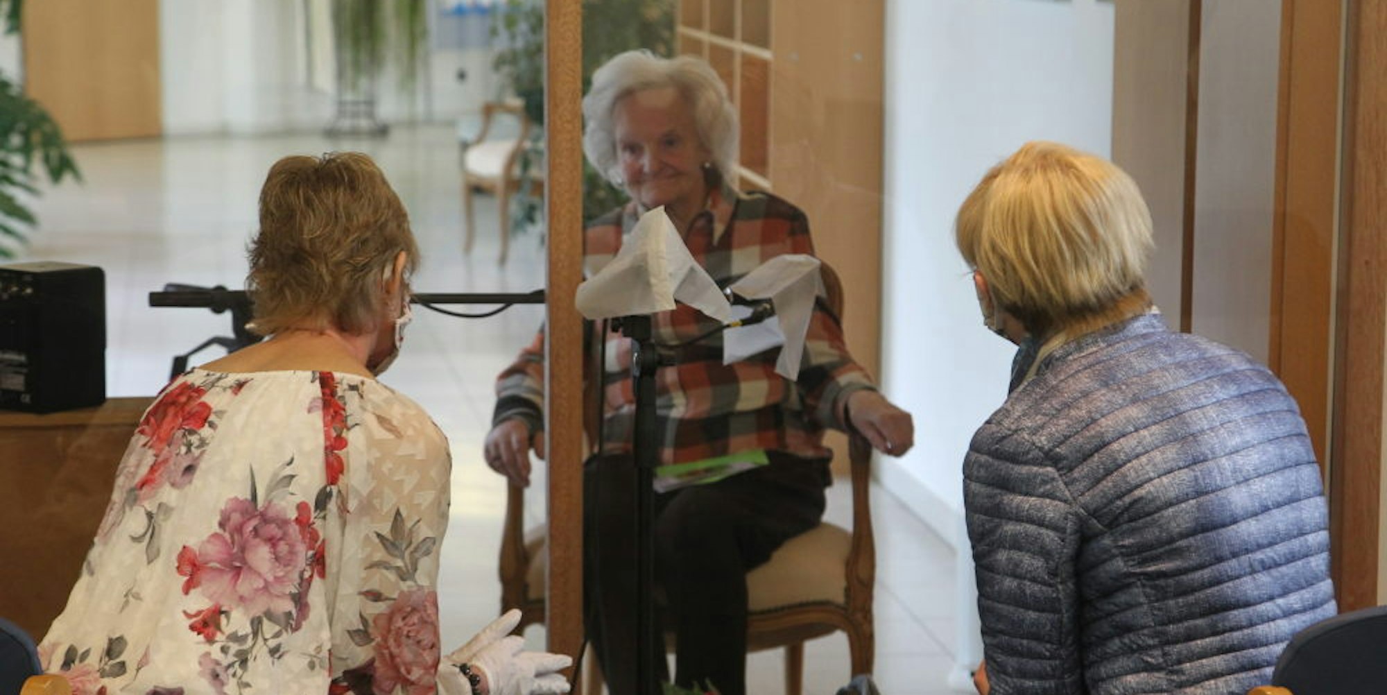 Eine Plexiglasscheibe trennt Heimbewohnerin Thea Rensing (Mitte) in Lohmar von ihren Töchtern Iris Rensing (links) und Petra Rink, die ihr zum 86. Geburtstag gratulierten.