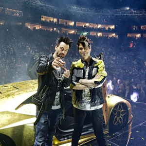 Andreas und Christian Ehrlich posieren in der Show-Pause vor ihrem goldenen Super-Flitzer in der Lanxess-Arena.