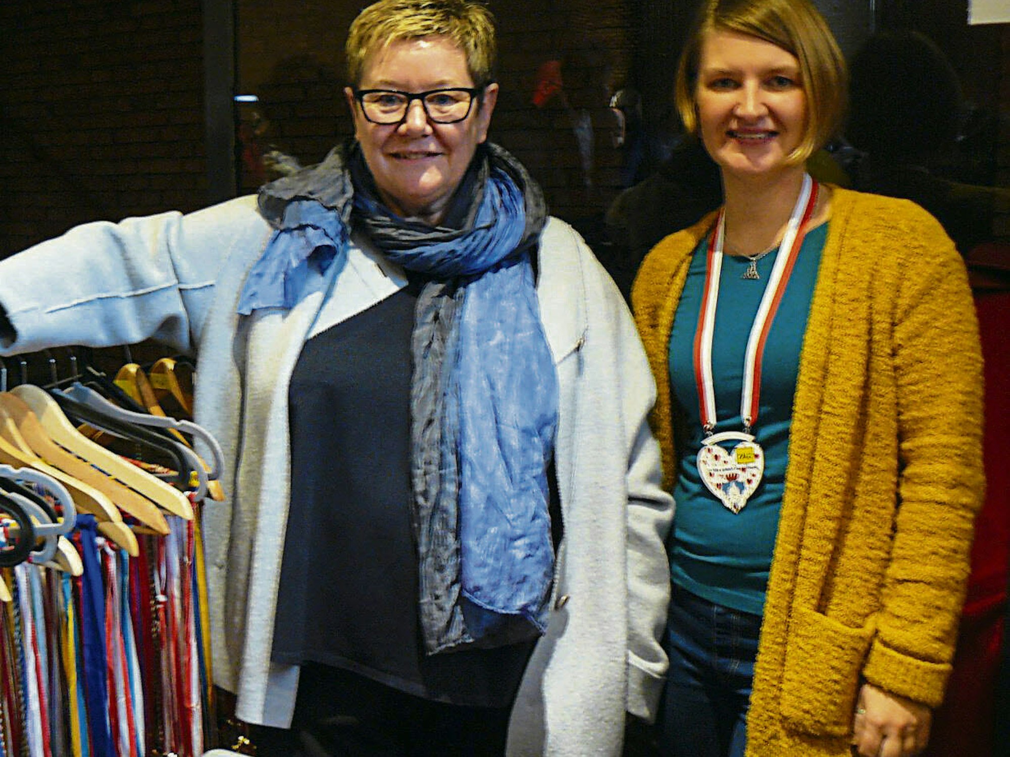 Frauke Mahr (links) und Alina Fast von „Lobby für Mädchen“ verkauften alte Karnevalsorden. Lydia Gödert (links) ließ eine interessierte Kundin in den Spiegel blicken.