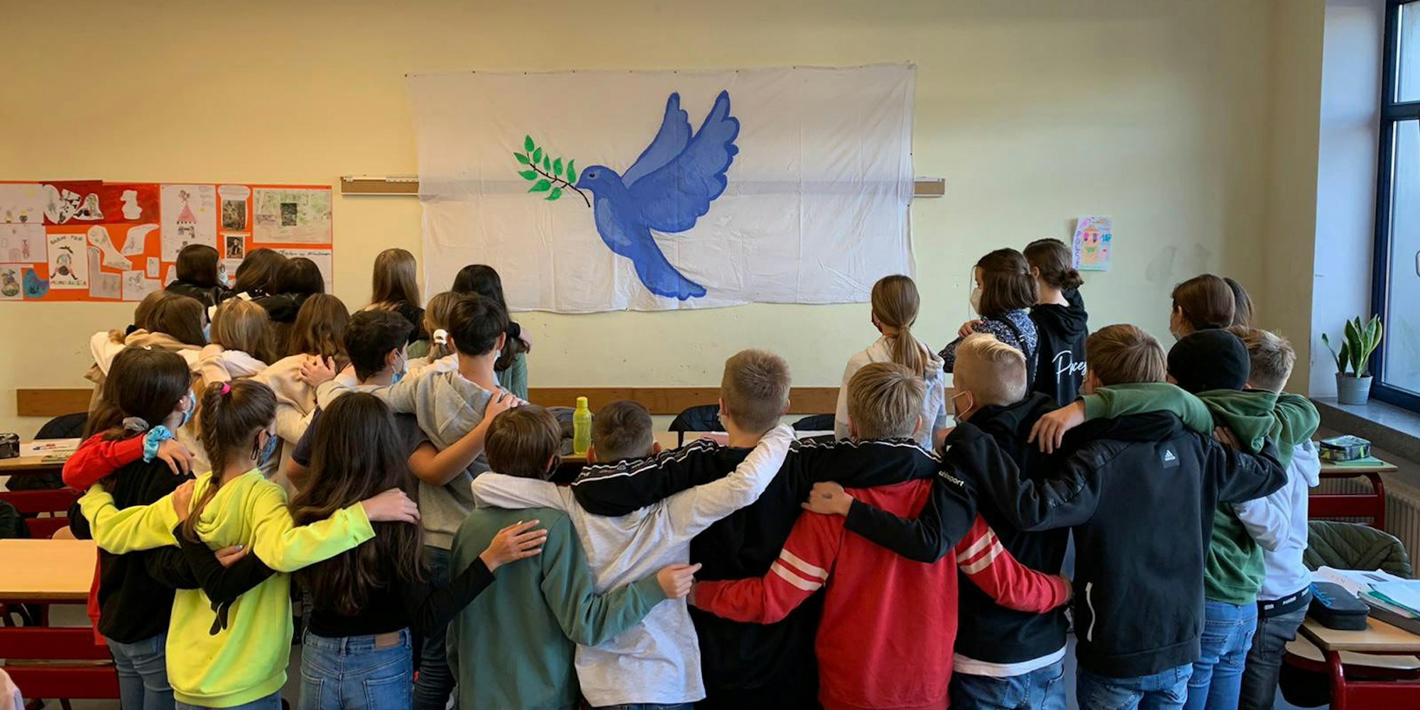 Die Gesamtschülerinnen und Gesamtschüler der Klasse 7d der Papst-Johannes-XXIII.-Gesamtschule versammeln sich vor einer Friedenstaube. Für ihre Lehrerin Birgit Mayer war das ein bewegender Moment.