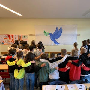 Die Gesamtschülerinnen und Gesamtschüler der Klasse 7d der Papst-Johannes-XXIII.-Gesamtschule versammeln sich vor einer Friedenstaube. Für ihre Lehrerin Birgit Mayer war das ein bewegender Moment.