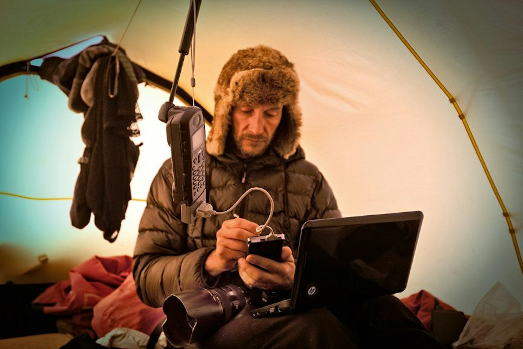 Mit Telefon und Laptop hält Sebastian Copeland unterwegs in der Arktis Kontakt zur Außenwelt.