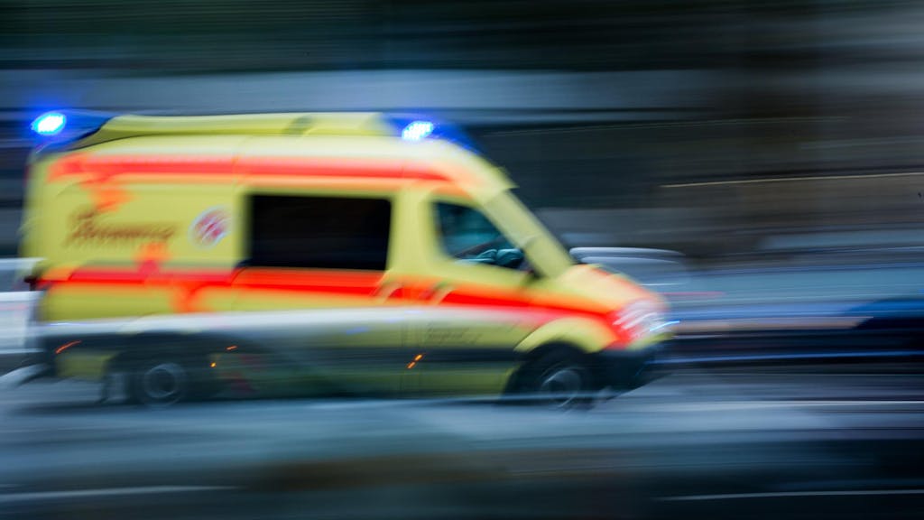 Ein Krankenwagen fährt mit eingeschaltetem Blaulicht eine Straße entlang.