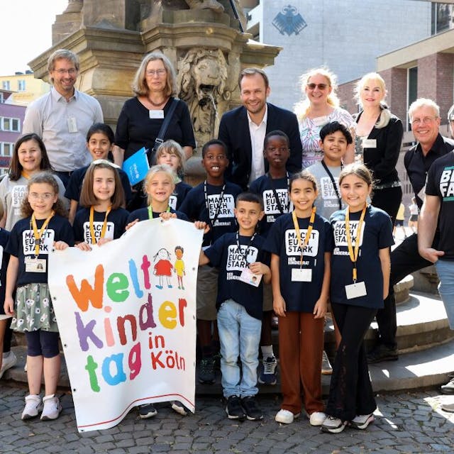 Der Kinderrat der Grundschule Merianstraße präsentiert das Programm des Kölner Weltkindertags gemeinsam mit Vertreterinnen und Vertretern der Veranstalter.
