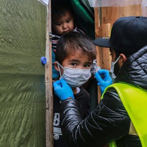 Ein Helfer legt einem Kind im Flüchtlingslager Moria auf der griechischen Insel Lesbos eine Schutzmaske an. Hilfsorganisationen warnen vor den verheerenden Folgen eines Ausbruchs der Corona-Pandemie.