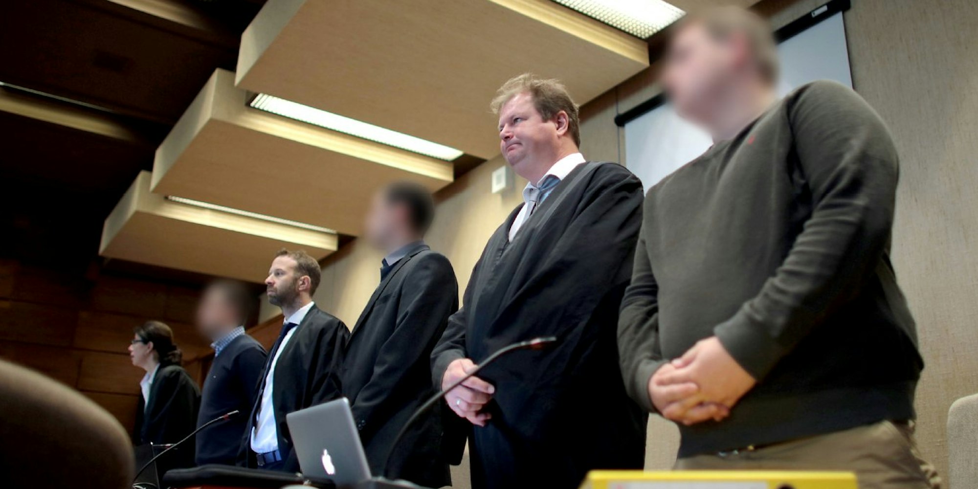 Die drei angeklagten Fußballfans stehen im Landgericht zwischen ihren Anwälten Alexandra Stolley (l), Tobias Nikolas Westkamp (3.v.l.) und Jan-Henrik Heinz (5.v.l.).