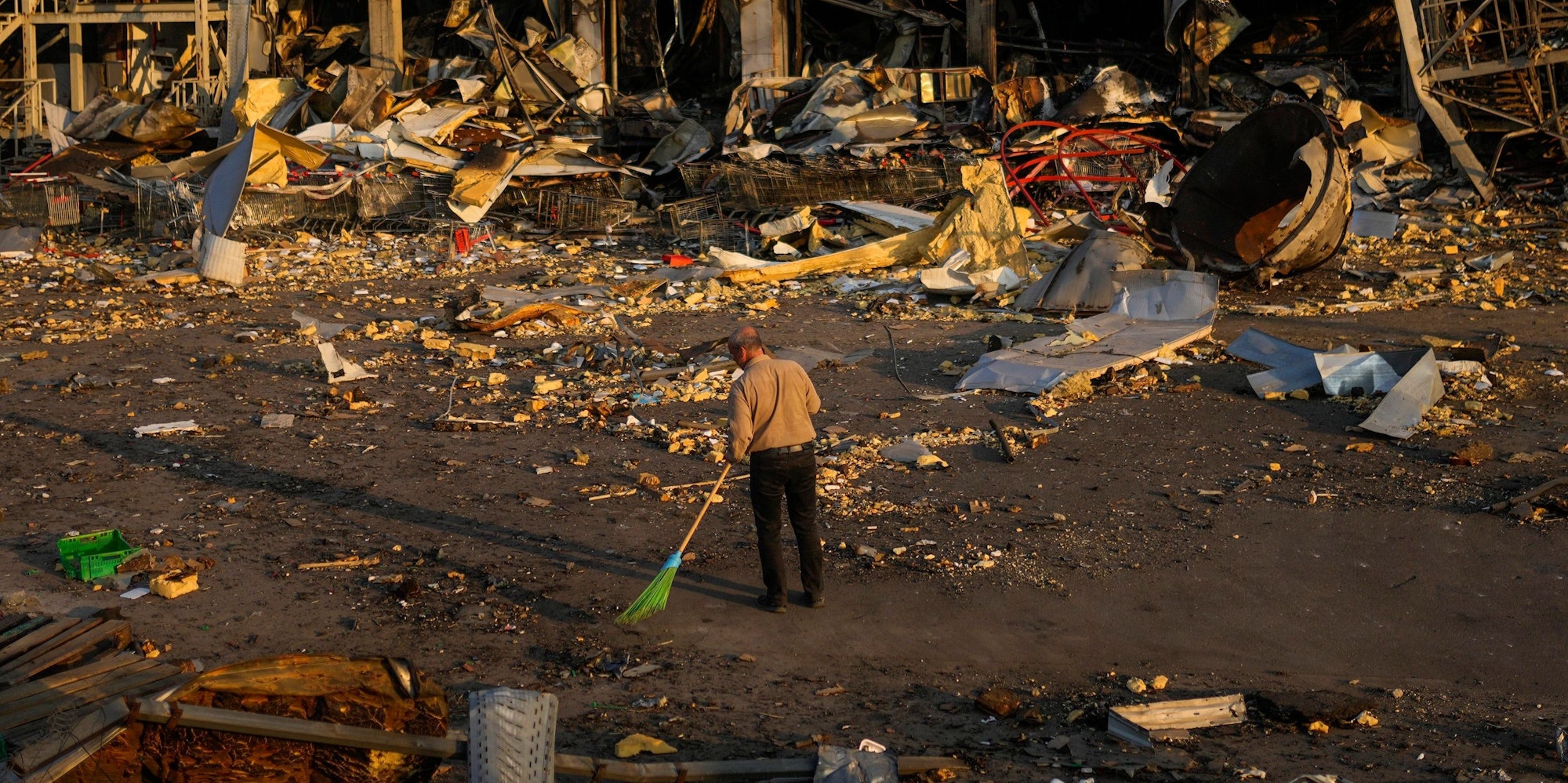 Zerstörung in Odessa: Ein Mann beseitigt Trümmer, nachdem ein russisches Geschoss ein Einkaufszentrum getroffen hat.