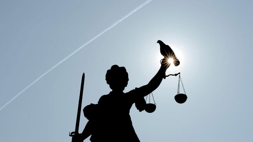 Eine Taube sitzt auf einer Justitia (Symbolbild)