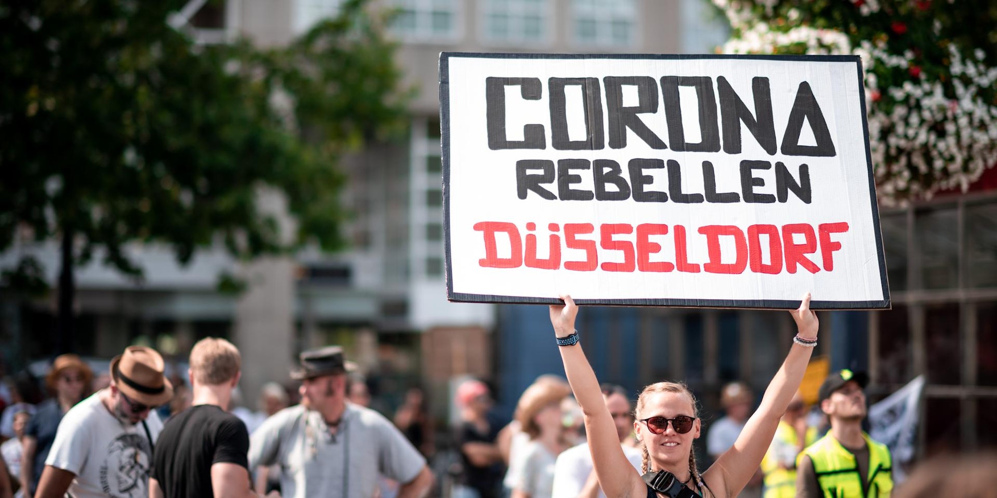 Schild mit Aufschrift Corona Rebellen Düsseldorf bei Demonstration