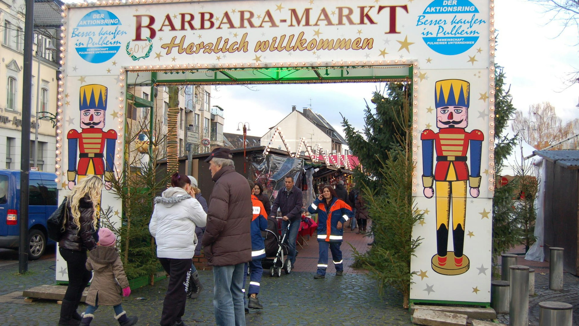 Menschen gehen durch das Eingangstor des Barbaramarkt in Pulheim.