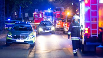 Einsatzfahrzeuge von Polizei, Feuerwehr und Rettungsdienst stehen in der Nacht an und auf einer Straße.