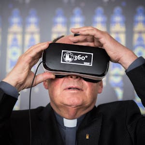 Der Dompropst Gerd Bachner probiert eine VR-Brille aus und ist von der Technik fasziniert.