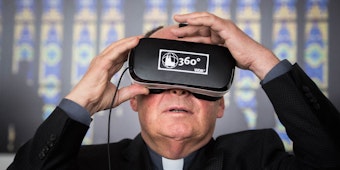 Der Dompropst Gerd Bachner probiert eine VR-Brille aus und ist von der Technik fasziniert.