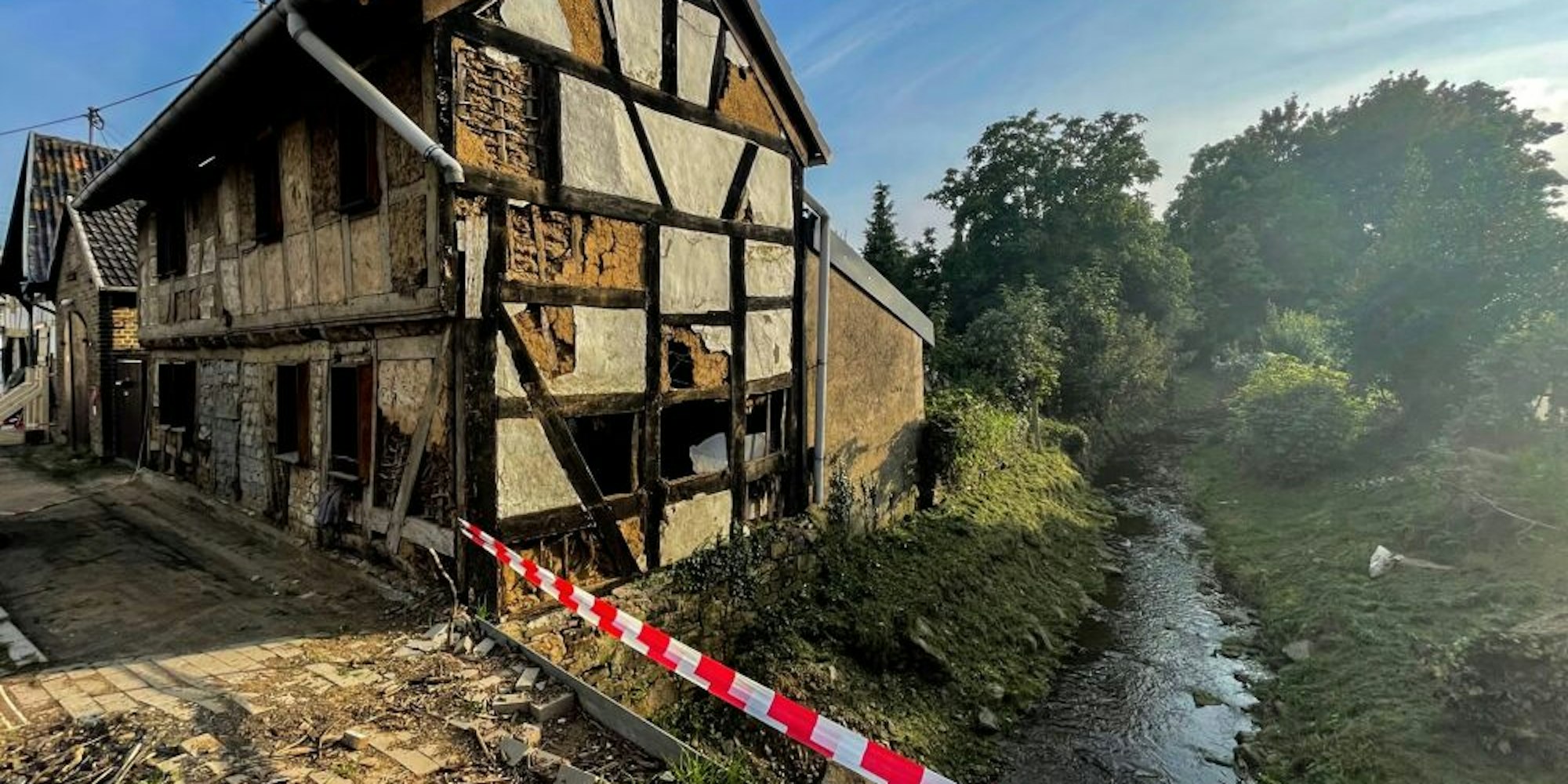 Der Steinbach fließt friedlich durch Schweinheim. Das Fachwerkhaus daneben war bereits vor der Flut stark beschädigt.