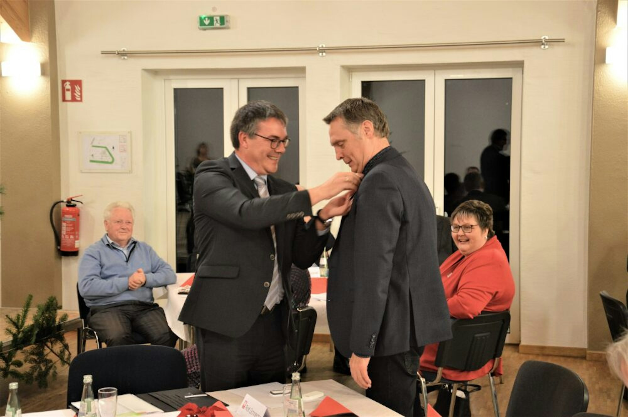 Das Goldene Ehrenzeichen der Caritas befestigt Stephan Jentgens am Revers des Anzugs von Rolf Schneider.