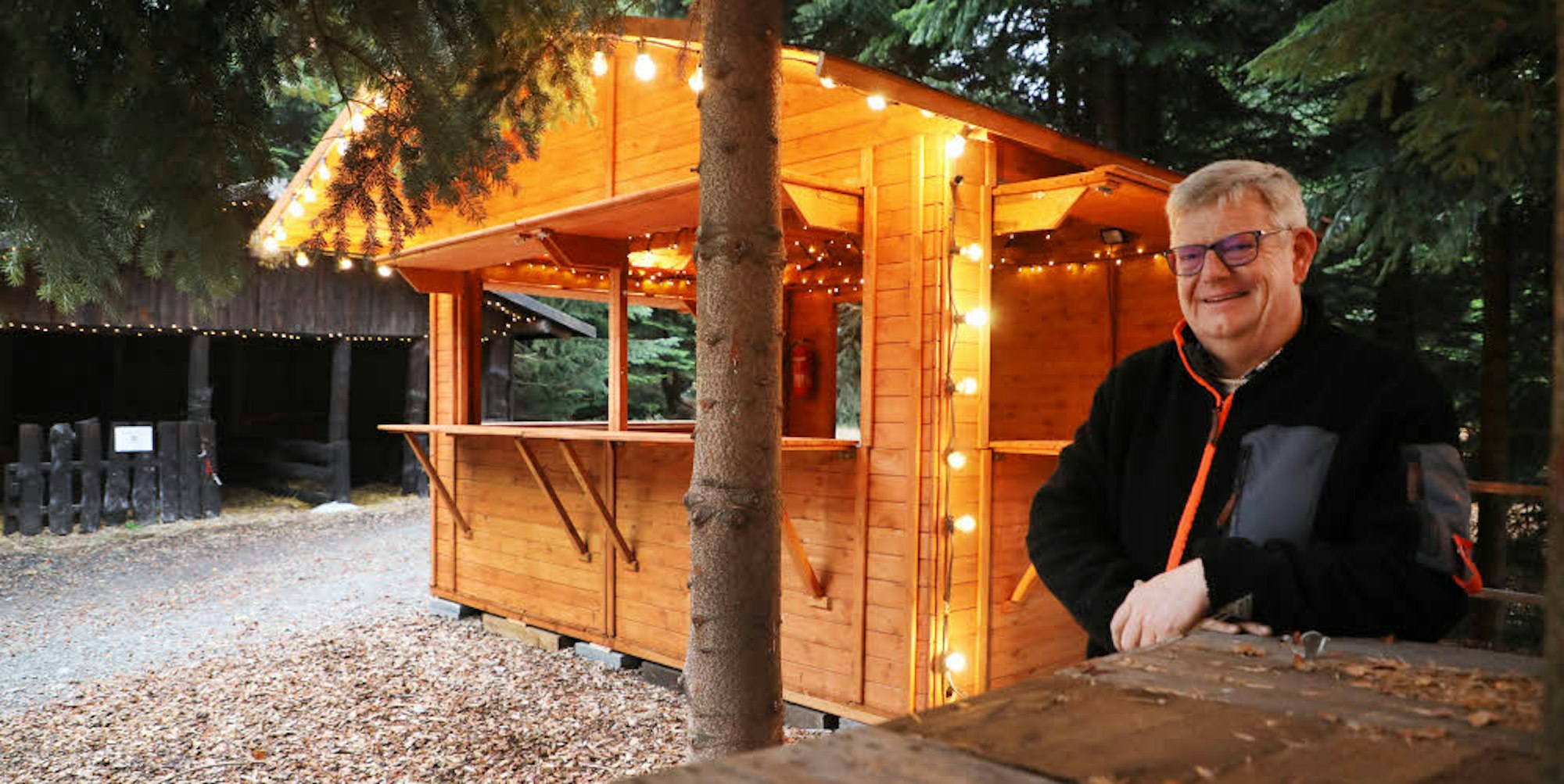 Neue Holzhäuschen und Tische unter hohen Christbäumen haben „gewachsene“ Hütten ersetzt: Meinolf Mütherich hat den Weihnachtsmarkt im Wald nach dem Ansturm von 2017 komplett umgekrempelt.