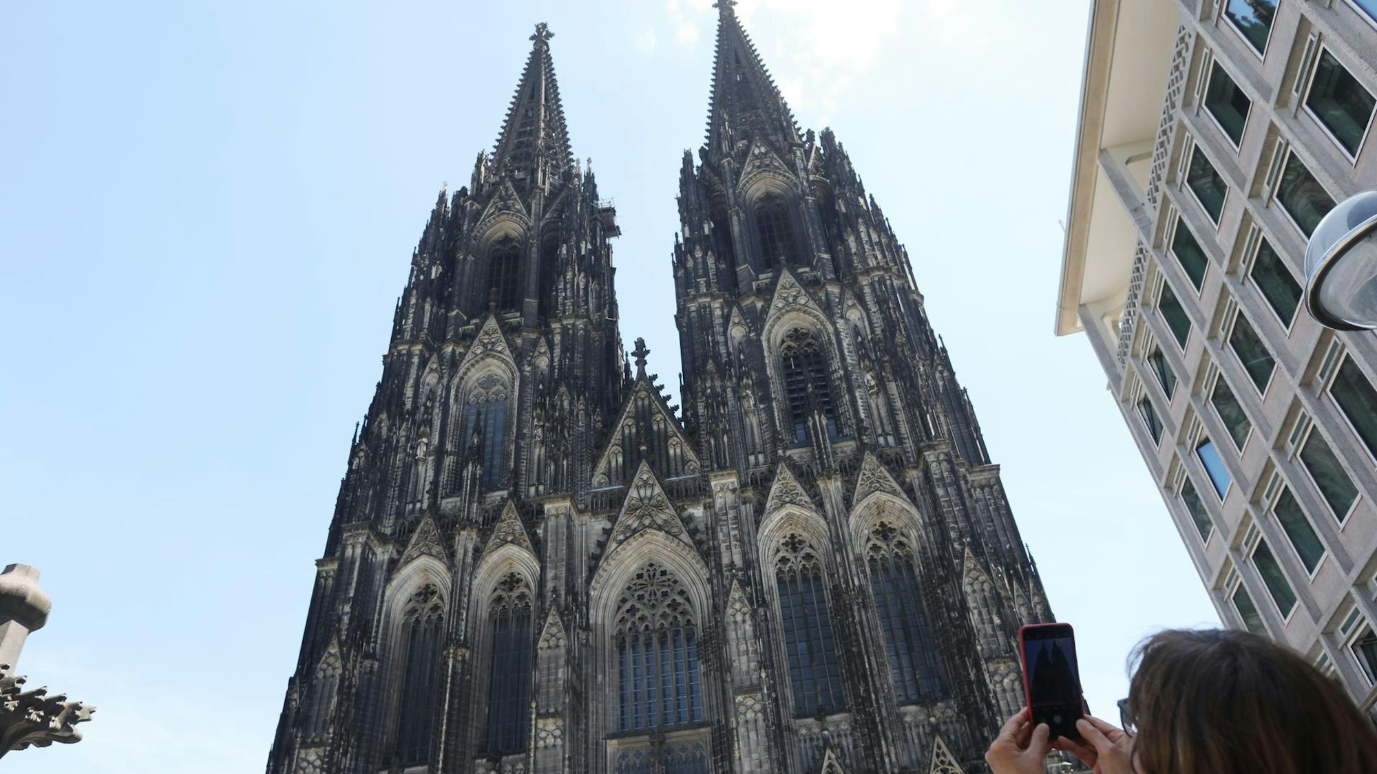 Kölner Dom, davor eine Frau, die ein Foto mit ihrem Handy macht
