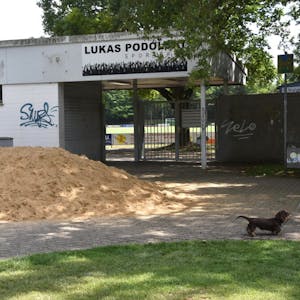 Der Sandhaufen vor dem Stadiontor ist Teil einer inszenierten Auseinandersetzung von zwei Promis. Das Material soll im Kindergarten „Regenbogenkobolde“ genutzt werden.