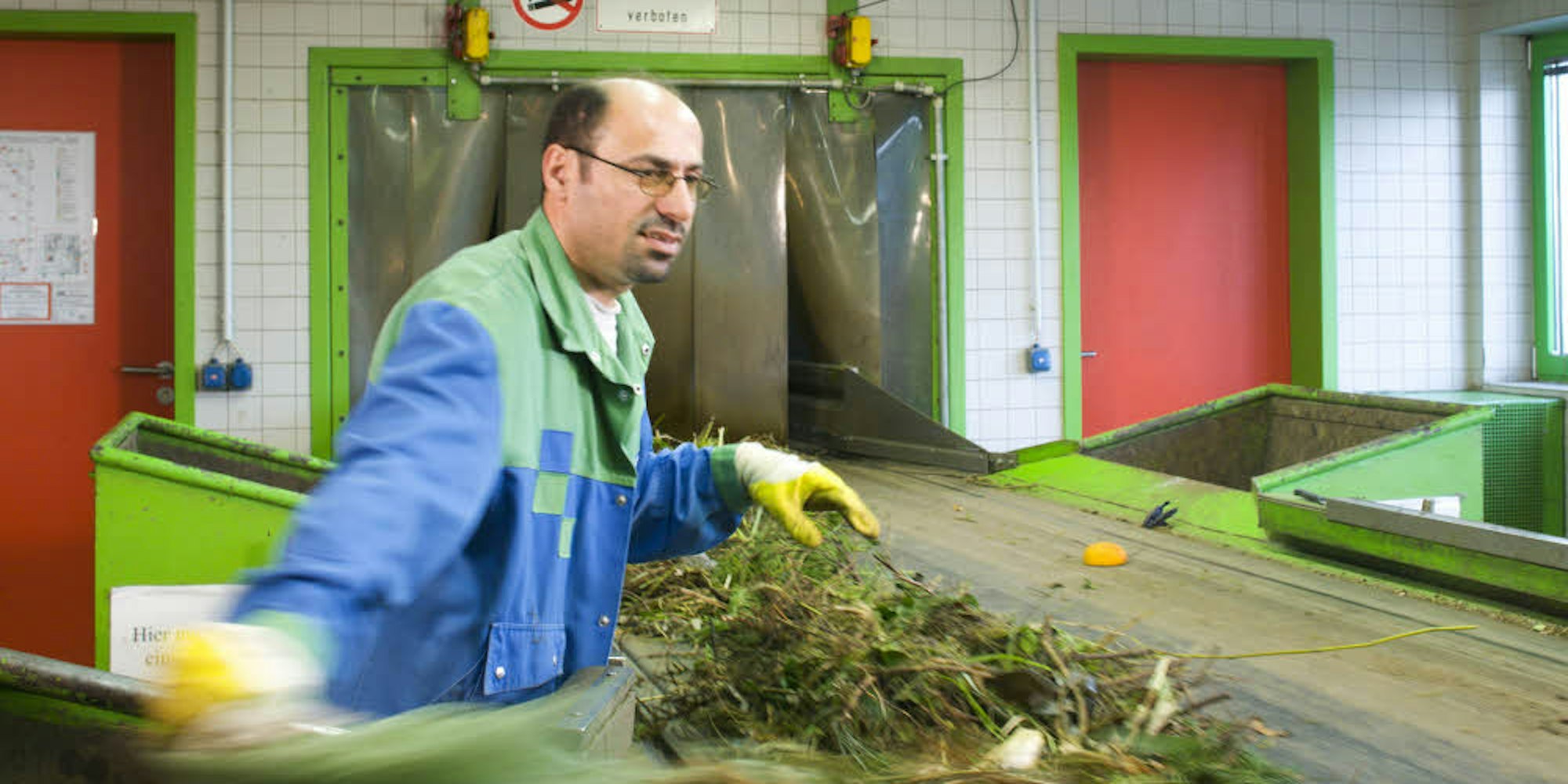 Raus damit! Am Band zur Kompostierungsanlage sortieren Mitarbeiter Störstoffe aus – darunter auch grüne Folienbeutel.