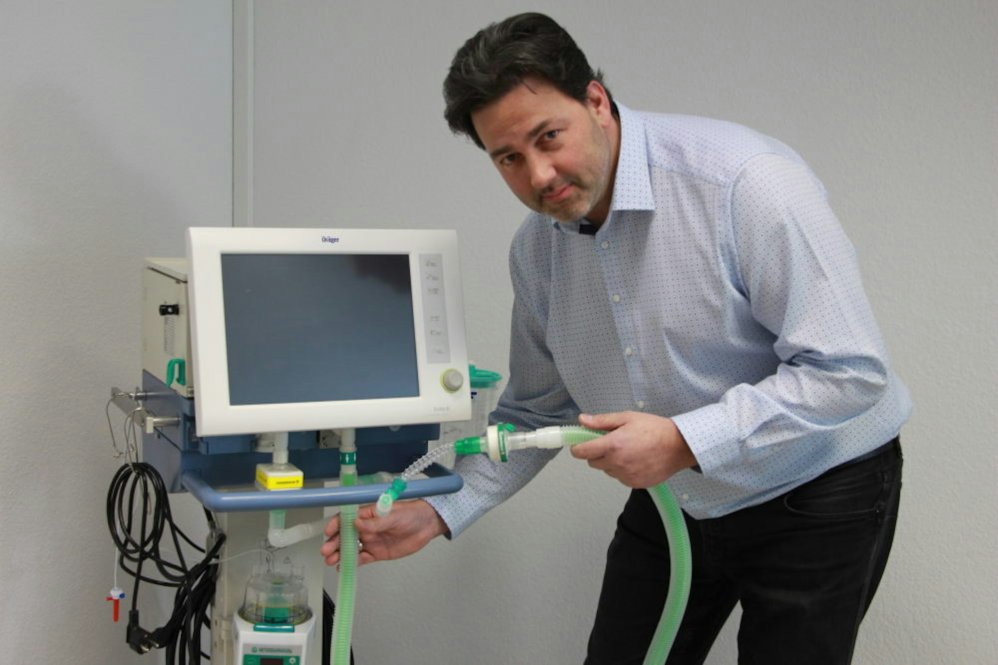 Prokurist Gerhard Otto zeigt einige Zubehörteile von Intersurgical für Beatmungsgeräte, zu erkennen an der grünen Farbe.