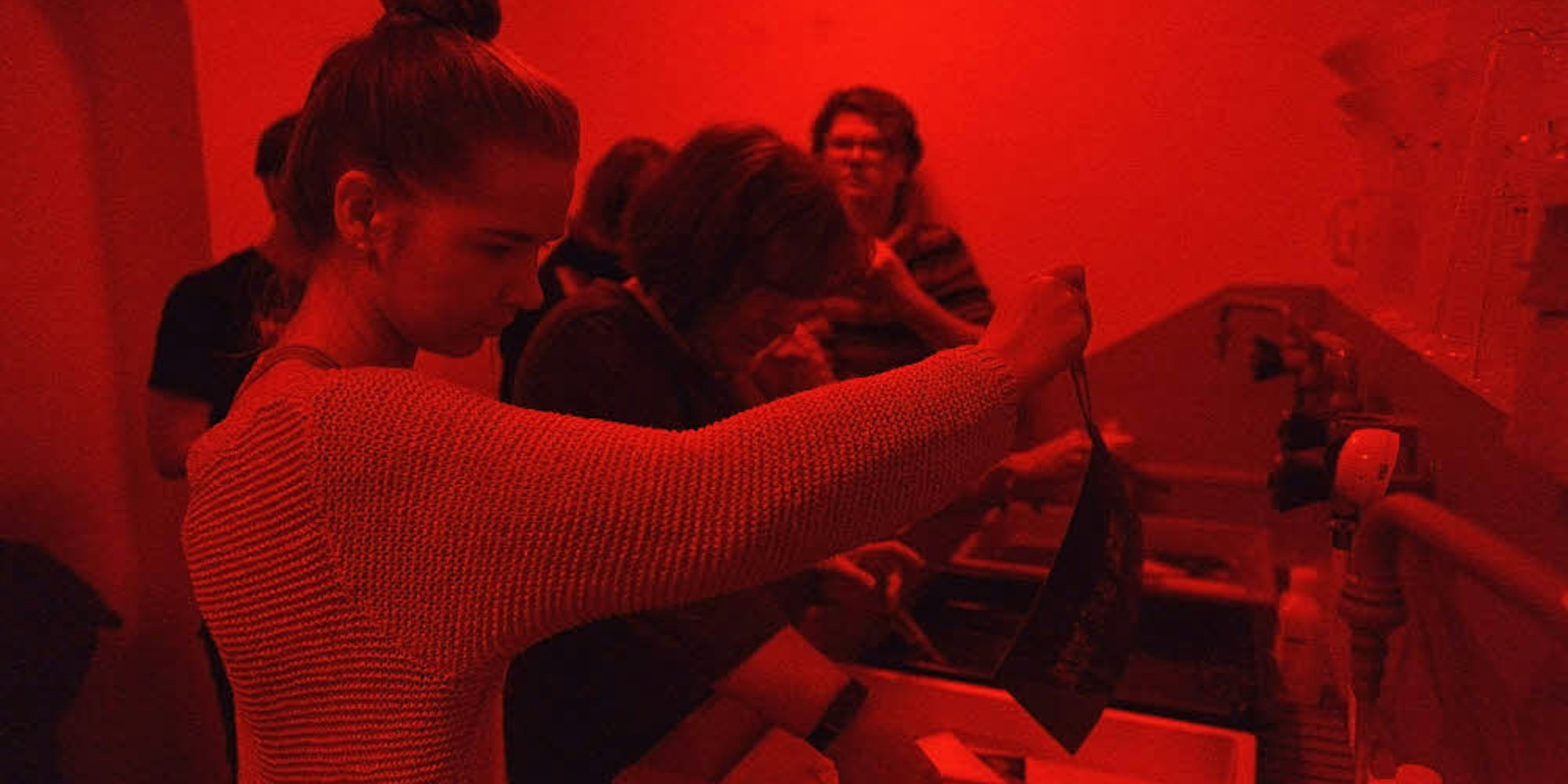 Im roten Schein der Dunkelkammer entwickeln die Teilnehmer des Workshops ihre Werke.
