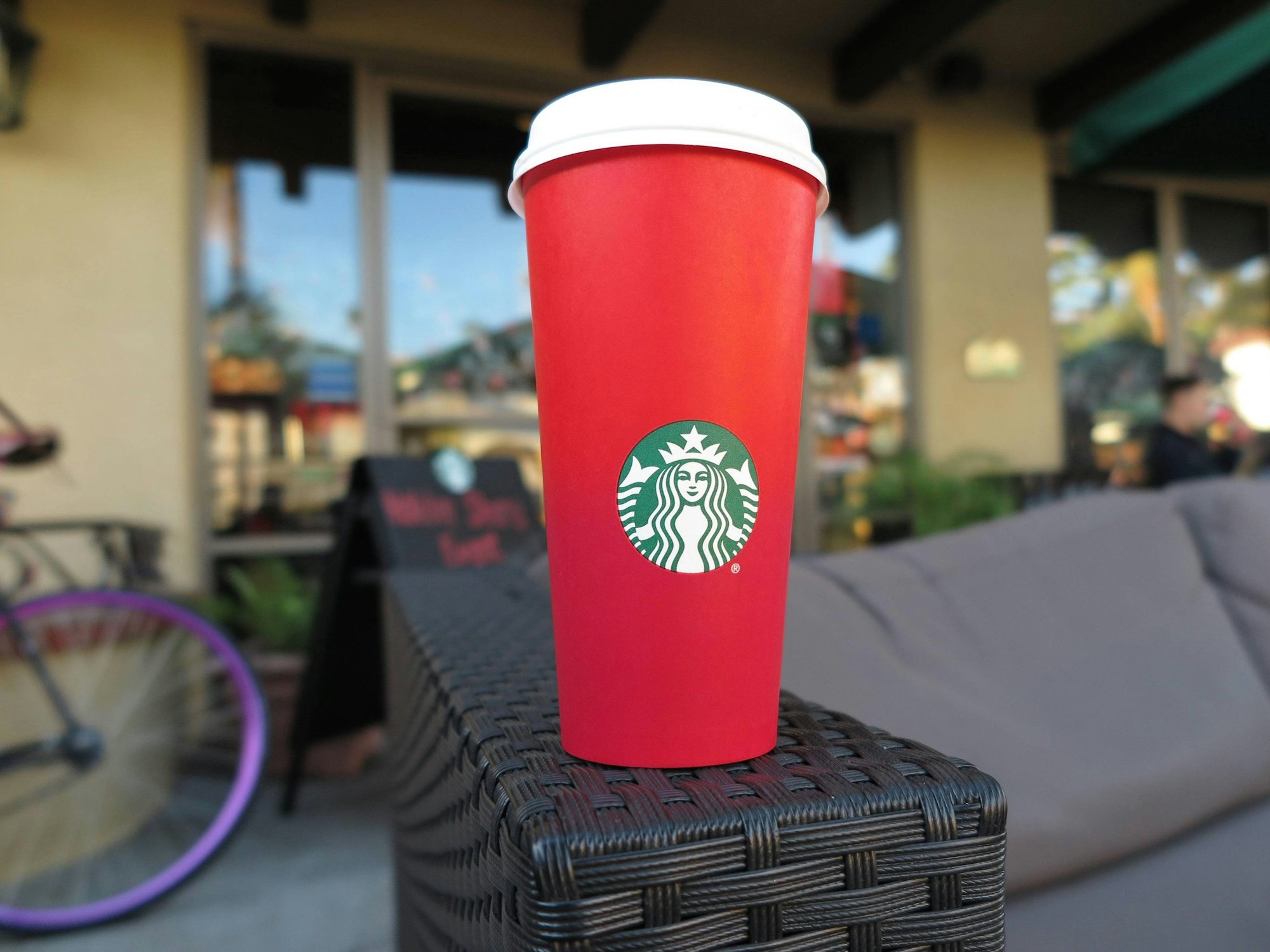 Ein roter To-go-Becher von Starbucks steht auf der Armlehne einer Couch.