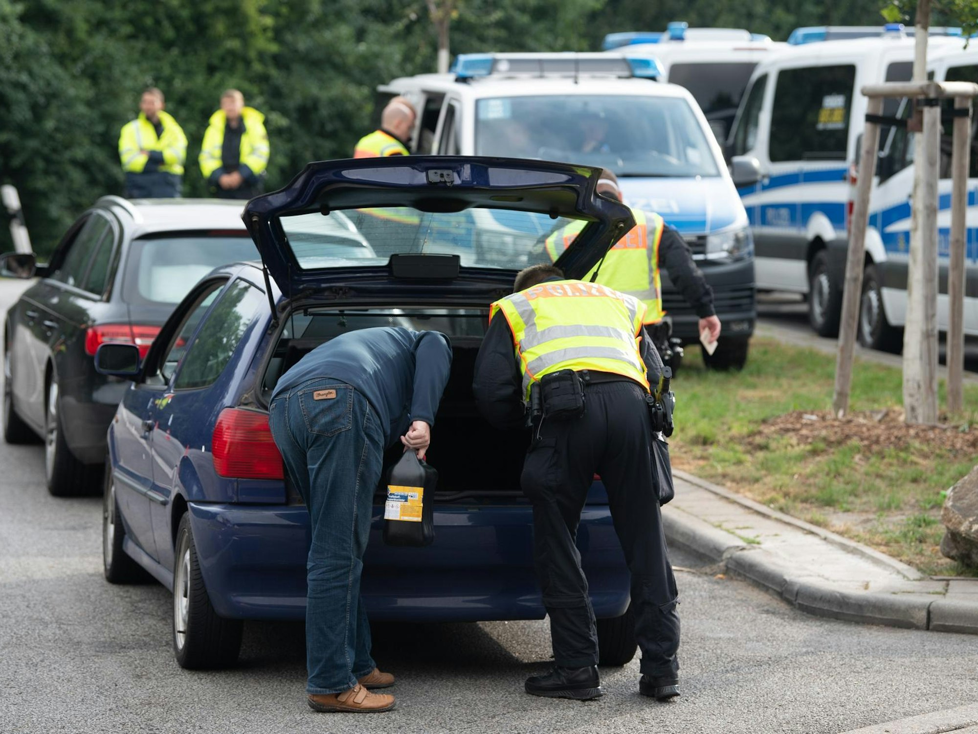 Polizeikräfte durchsuchen den Kofferraum eines Pkw.