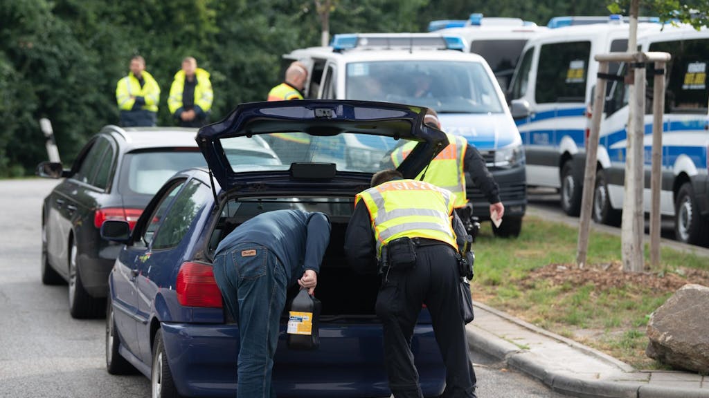 Polizeikräfte durchsuchen den Kofferraum eines Pkw.