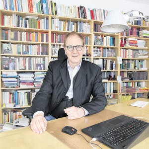 Michael Opielka arbeitet in seinem Büro mitten in Siegburg vor einem Regal mit unzähligen Büchern.
