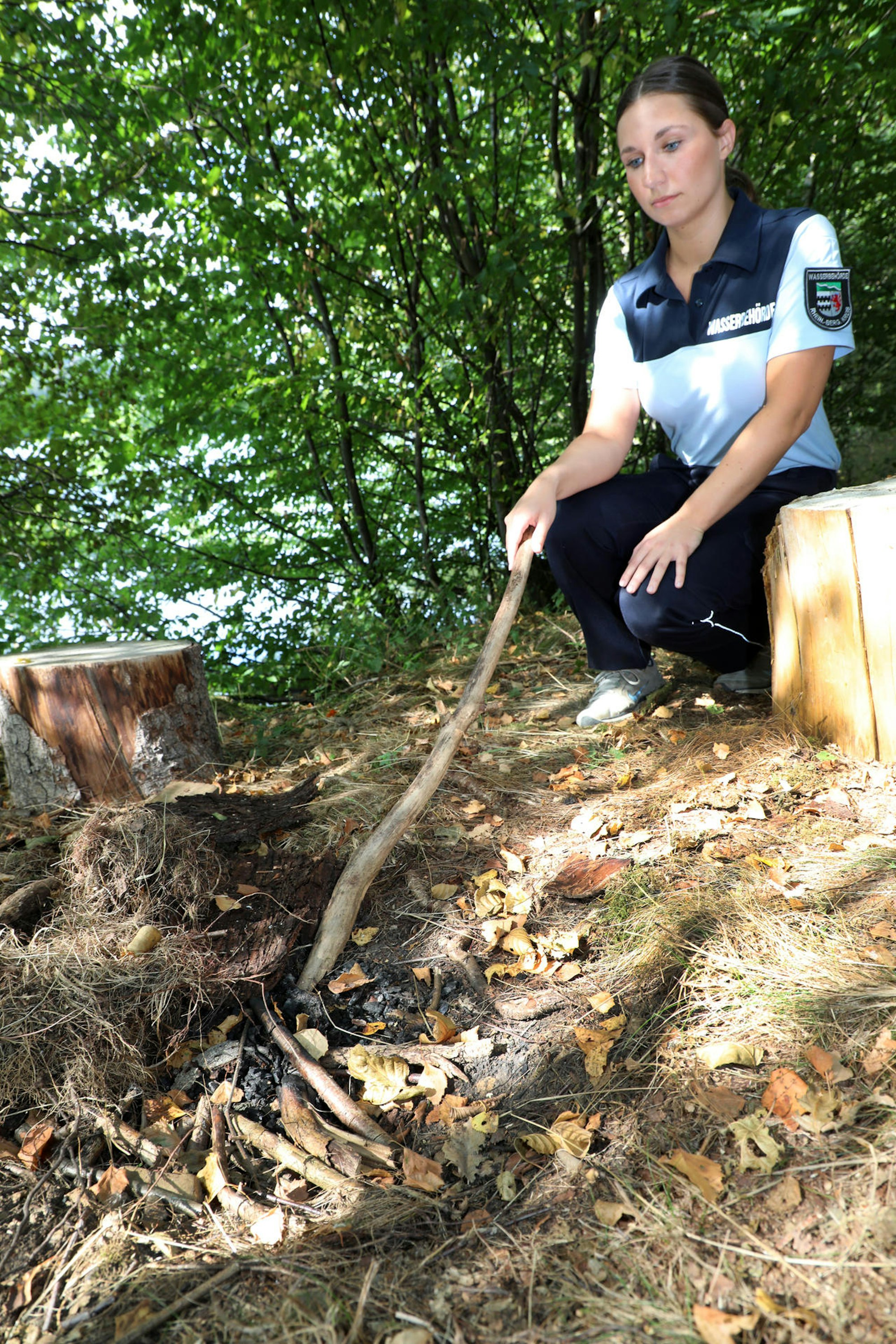 Rebecca Theis legt eine Feuerstelle mitten im trockenen Unterholz am Wasser frei.