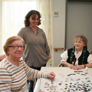 Gertrud Janser (r.) und Marga Kirfel puzzeln gemeinsam, Sandra Werkmeister ermuntert die beiden Seniorinnen.
