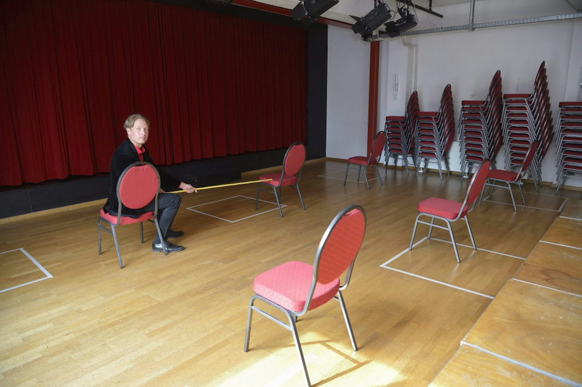 Theas-Leiter David Heitmann demonstriert, wie die Stühle im Saal aufgestellt werden müssen – mit Abstand.