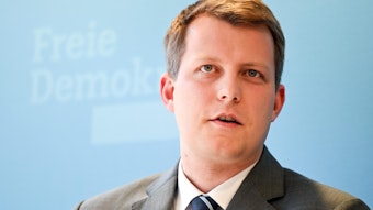 Der FDP-Politiker Henning Höne steht vor einer hellblauen Wand, er ist 35 Jahre alt.