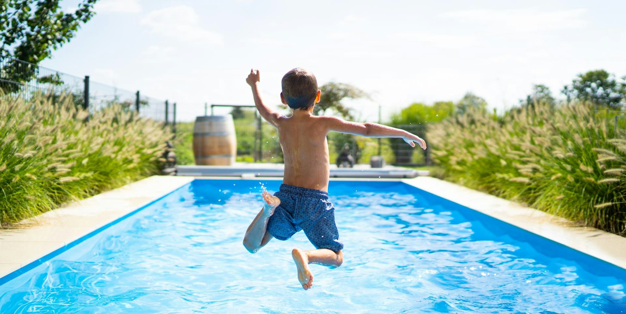 Junge-springt-mit-Anlauf-in-einen-Swimmingpool