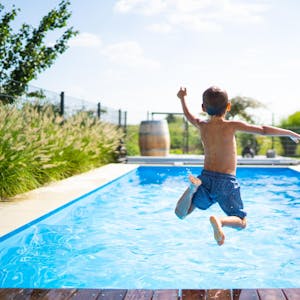 Junge-springt-mit-Anlauf-in-einen-Swimmingpool