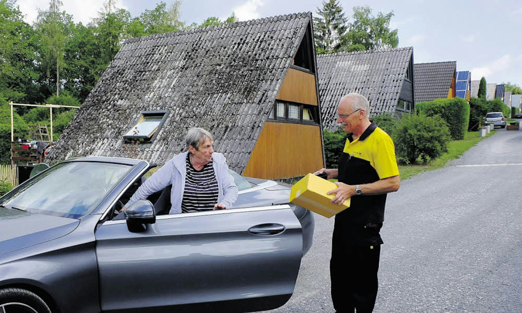 Postzusteller Bernhard Plötzer hat Feriendorf-Bewohnerin Christine Kugelmeier „abgefangen“ und händigt ihr ein Päckchen aus.