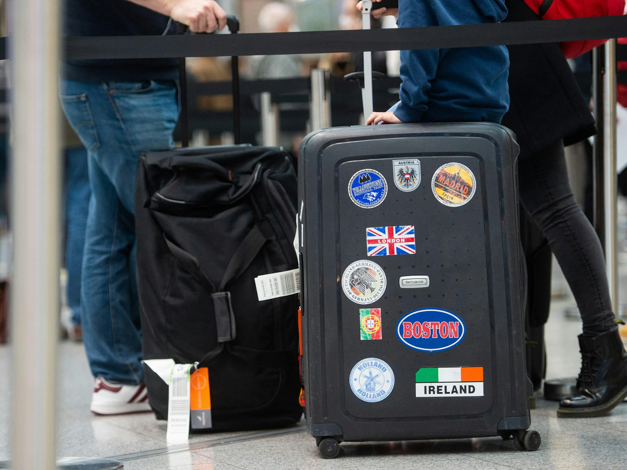 Reisende stehen in einem Flughafen einer Schlange mit ihrem Gepäck.