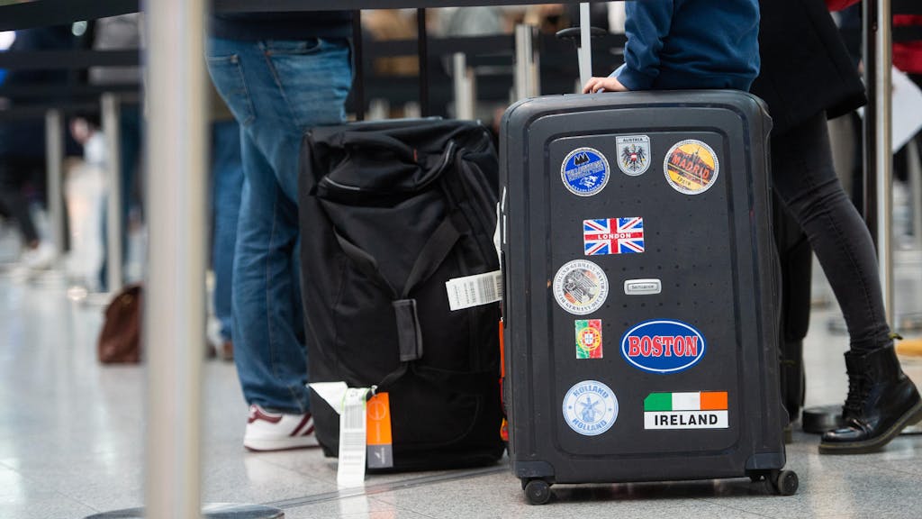 Reisende stehen in einem Flughafen einer Schlange mit ihrem Gepäck.
