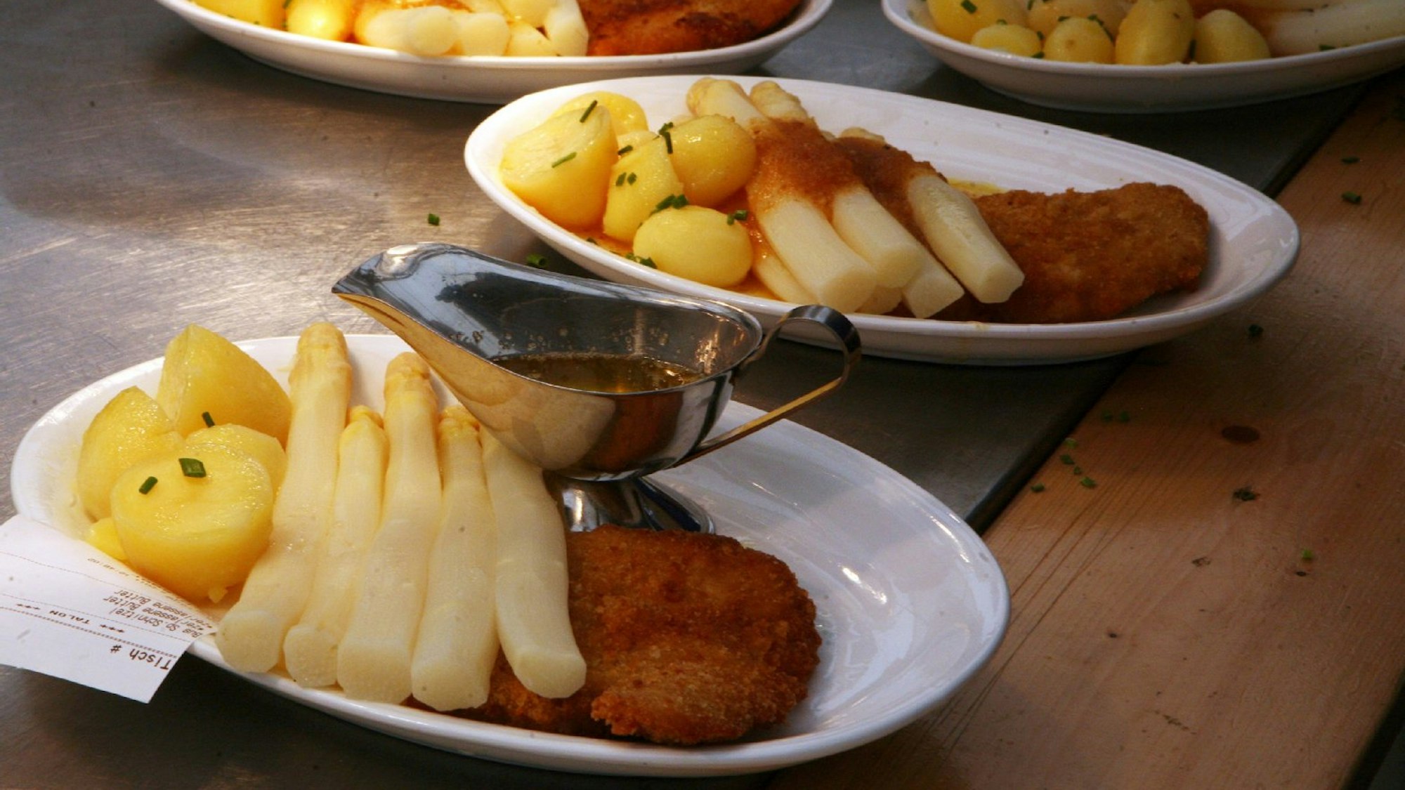 Spargel, Kartoffeln und Schnitzel, auf Tellern angerichtet.