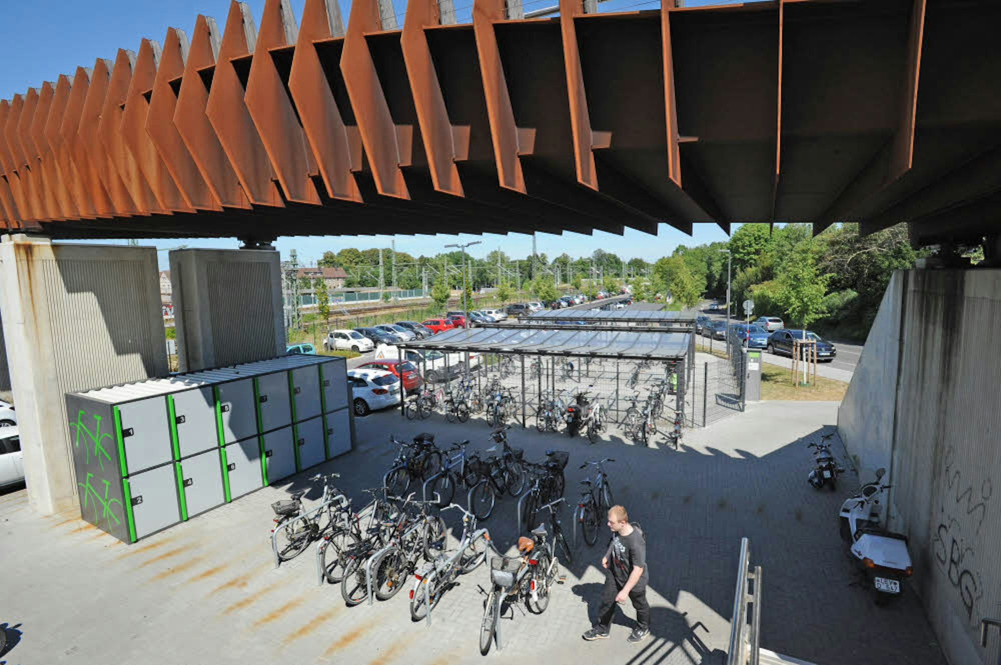 Individuelle Fahrrad-Mietboxen, ein abgeschlossener Käfig und ungeschützte Abstellmöglichkeiten im Freien sind an der Ostseite der Bahnhofsbrücke, an der Lützenkirchener Straße, vorhanden.