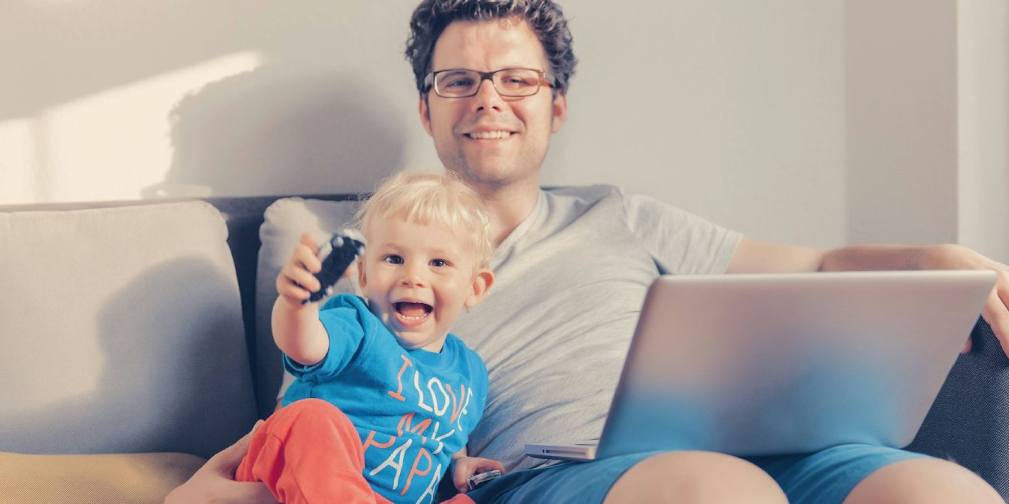 Multitasking Daddy: Vater mit Laptop und Kind.