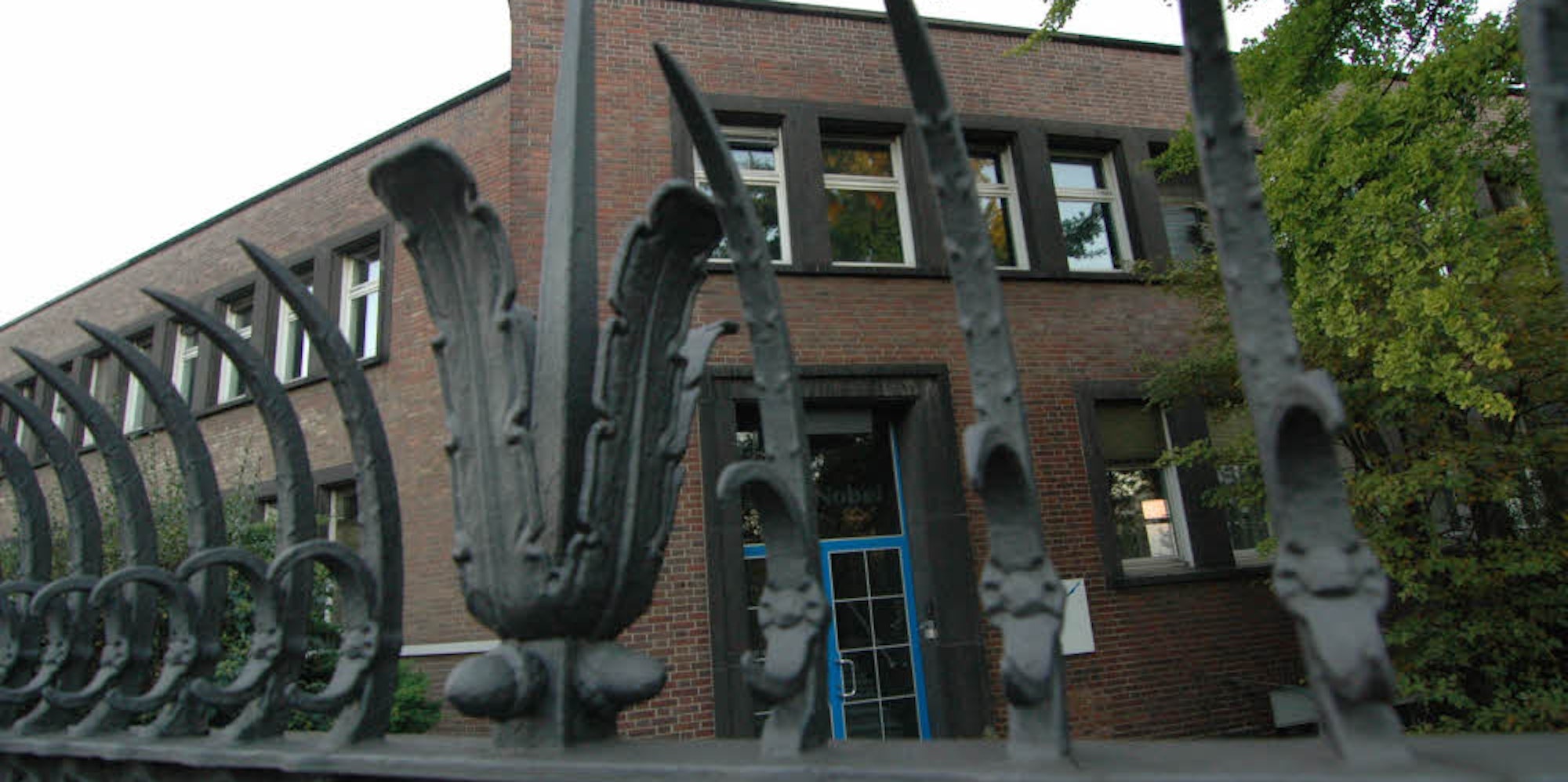 Das Gebäudeportal und die kunstvolle Metall-Einfriedung an der Vitalisstraße.