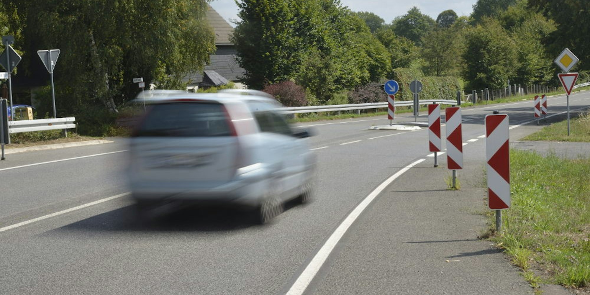 Rot-weiße Warnbaken vor einer Straßeneinmündung sollen Autofahrern helfen, sich in den Verkehr einzufädeln.
