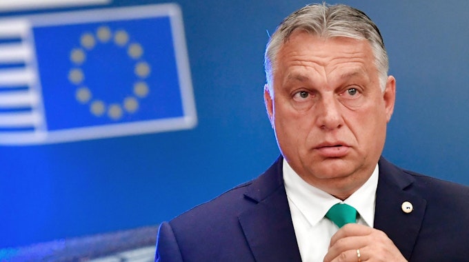 Ungarns Ministerpräsident Viktor Orban schreiben fasst sich an die Krawatte.