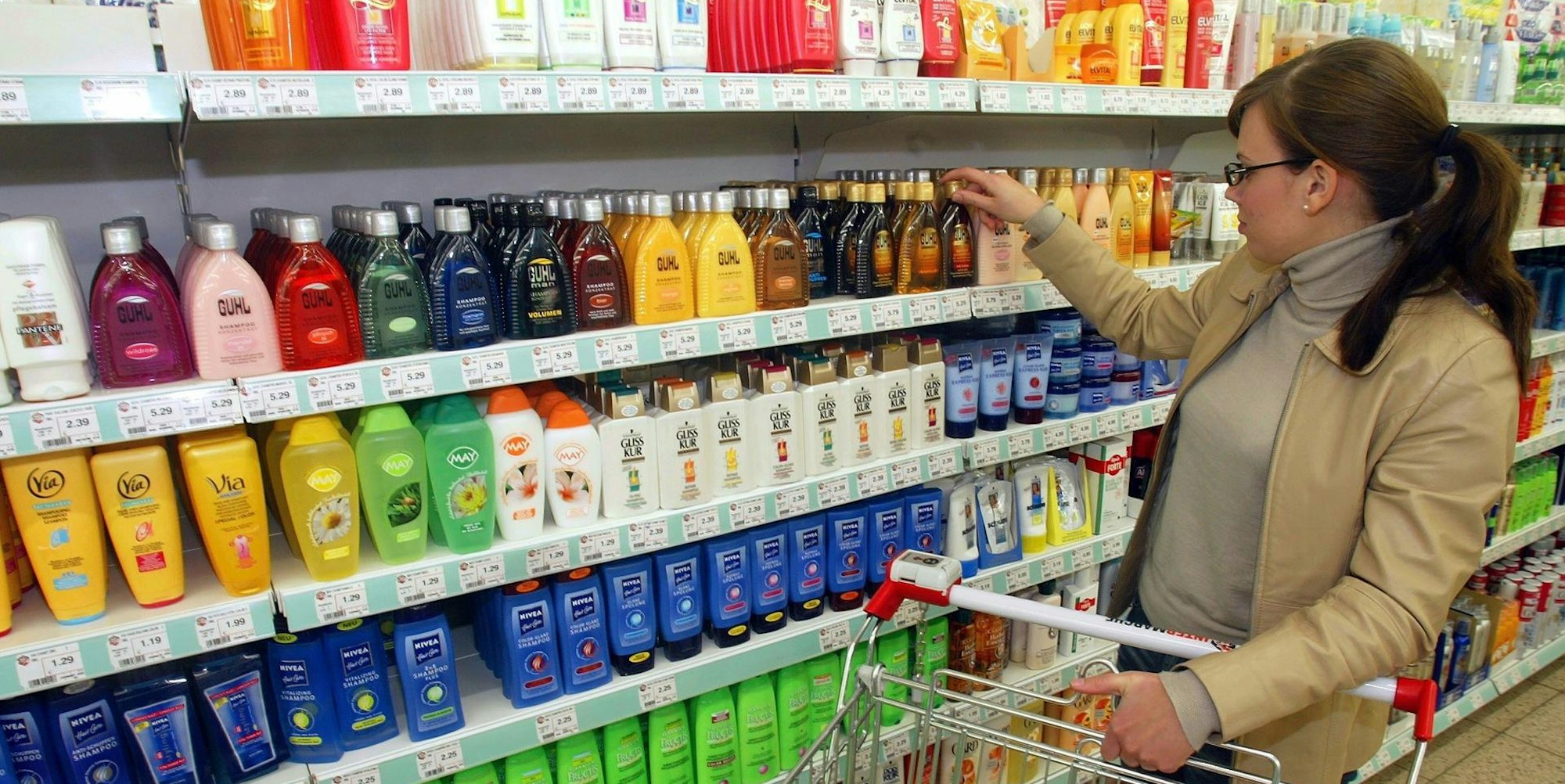 Frau nimmt Shampoo aus dem Supermarktregal
