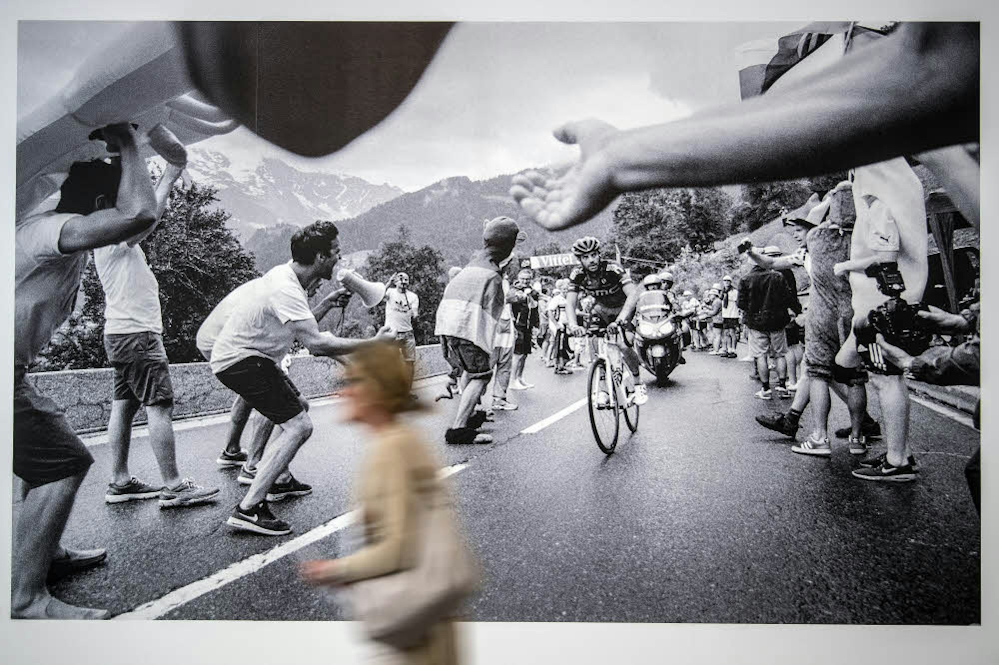 Eine Besucherin geht  in Düsseldorf  in der Foto-Gruppenausstellung „Mythos Tour de France“ an einem Bild von Nicola Mesken vorbei.