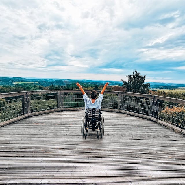 Eine Rollstuhlfahrerin auf einer Aussichtsplattform des Baumwipfelpfads Panarbora in Wadbröl.