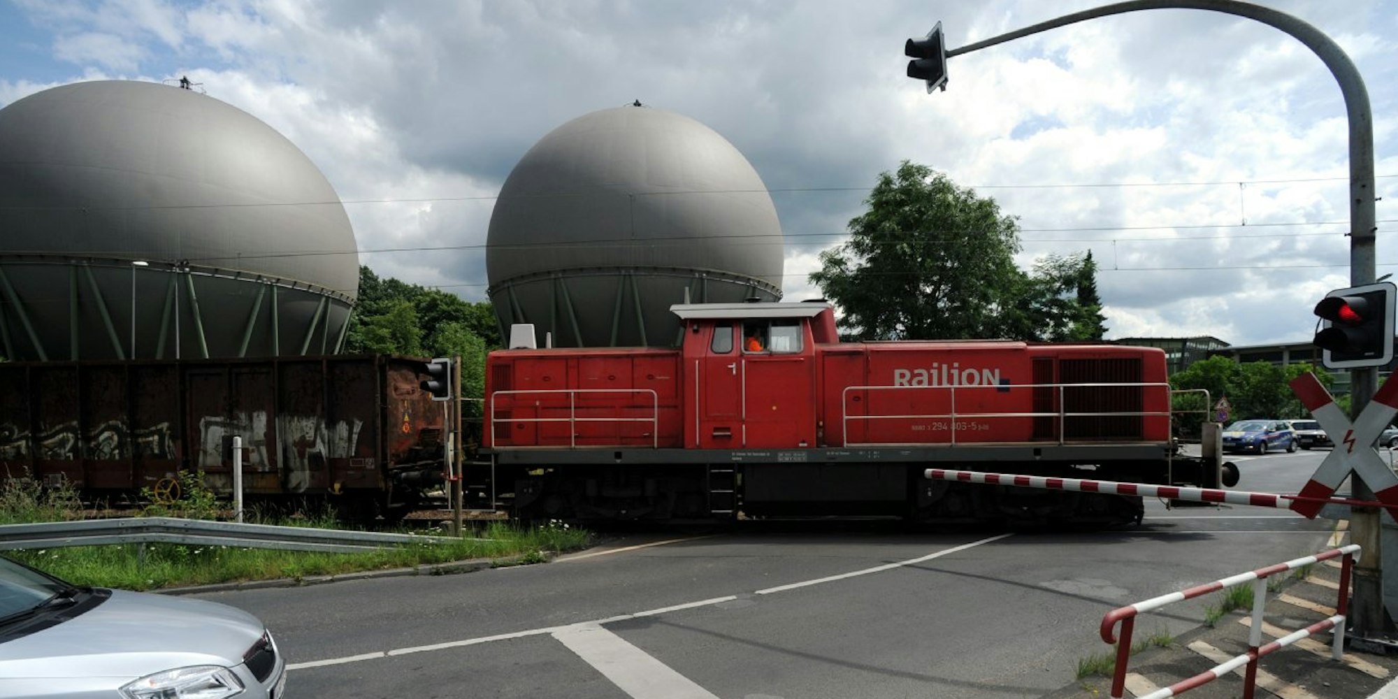 Ein Güterzug fährt vor den Gaskesseln an der Piccoloministraße entlang.