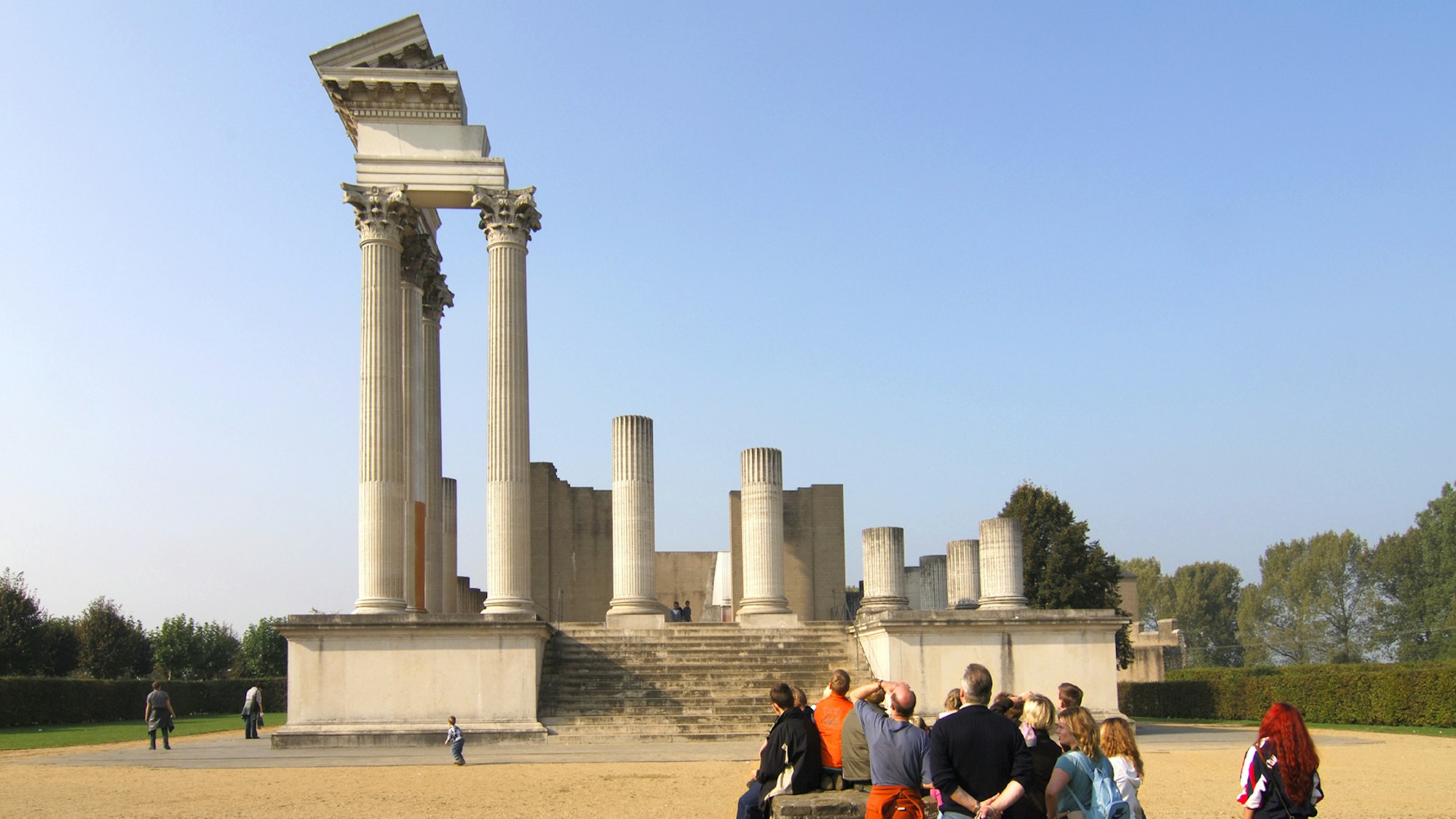 Besucher blicken auf die Ruine eines römischen Tempels.