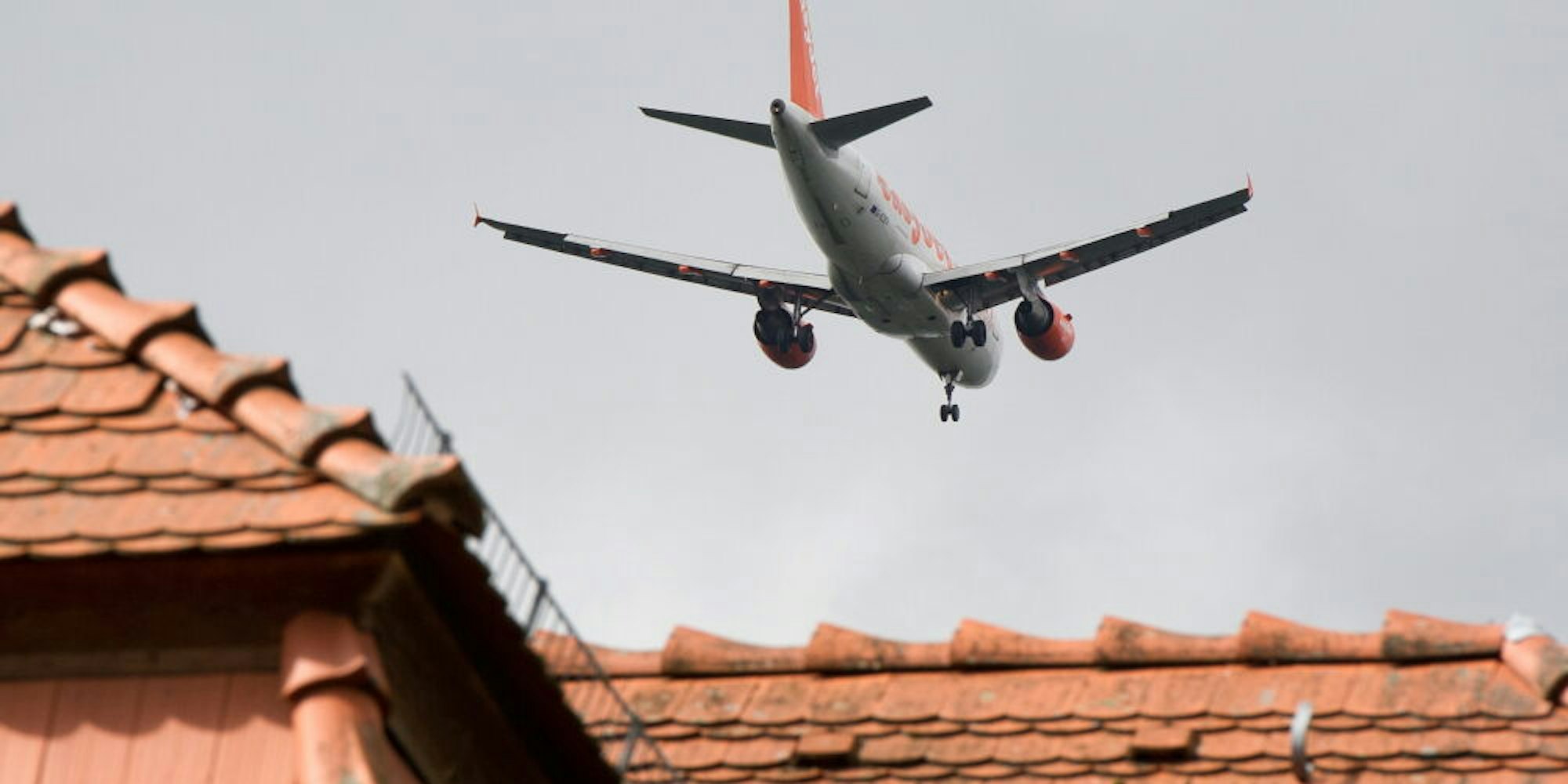 Ein Flugzeig fliegt über ein Hausdach (Symbolbild)